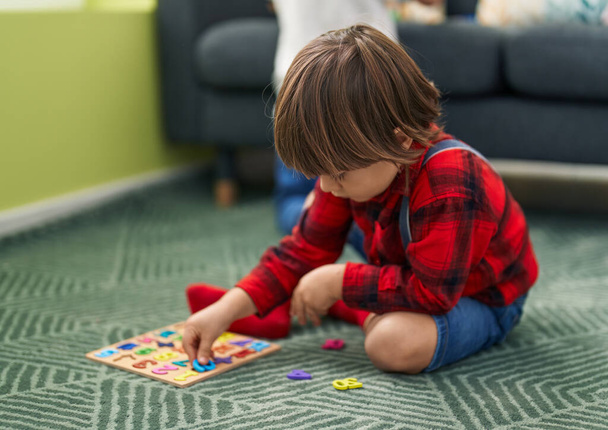 Adorable toddler playing with maths game sitting on floor at home - Photo, Image