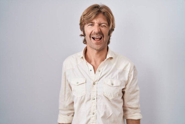 Middle age man standing over isolated background winking looking at the camera with sexy expression, cheerful and happy face.  - Foto, Bild