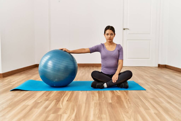 Young latin woman stretching using fit ball at sport center - Photo, Image