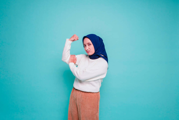 Excited Asian Muslim woman wearing a white shirt and hijab showing strong gesture by lifting her arms and muscles smiling proudly - Φωτογραφία, εικόνα