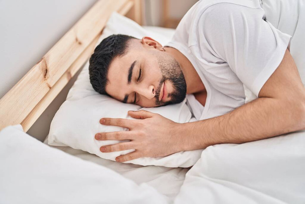Young arab man lying on bed sleeping at bedroom - Foto, afbeelding