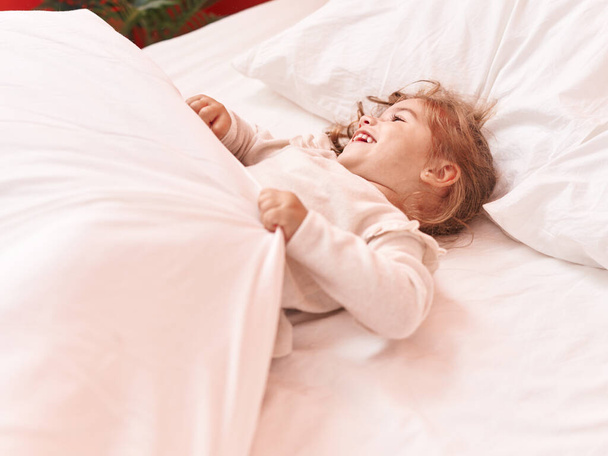 Чарівна іспаномовна дівчина посміхається впевнено лежить на ліжку в спальні
 - Фото, зображення