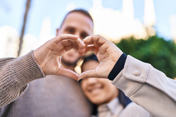 Man and woman smiling confident doing heart symbol with hands at street - Photo, image