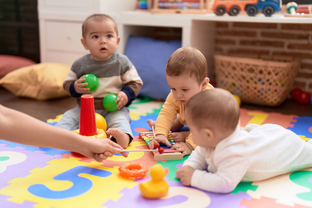Group of toddlers playing with toys sitting on floor at kindergarten - Фото, зображення