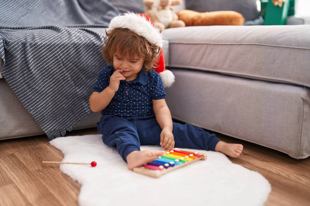 Schattige Spaanse peuter met kerstmuts die thuis xylofoon speelt - Foto, afbeelding