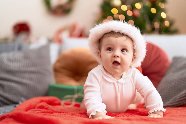 Очаровательный малыш в рождественской шляпе лежит дома на диване. - Фото, изображение