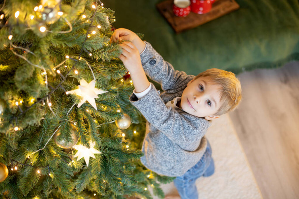 Cute preschool child, blond boy with pet dog, playing in decorated Christmas room at home - Foto, imagen