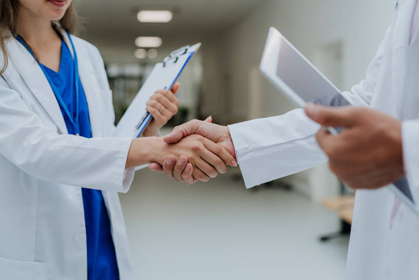 Close-up of doctors shaking hands at a hospital corridor. - Foto, Imagem