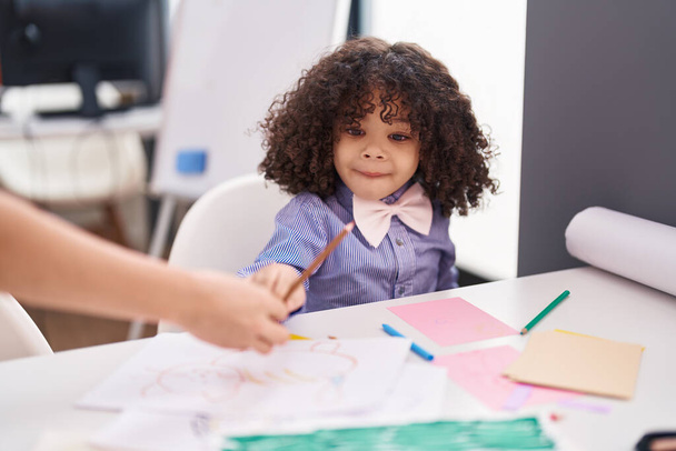 Africain américain tout-petit élève préscolaire assis sur la table tenant crayon de couleur à la maternelle - Photo, image
