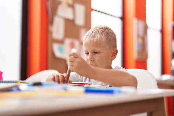 Suloinen lapsi opiskelija piirustus kannettavan istuu pöydällä luokkahuoneessa - Valokuva, kuva