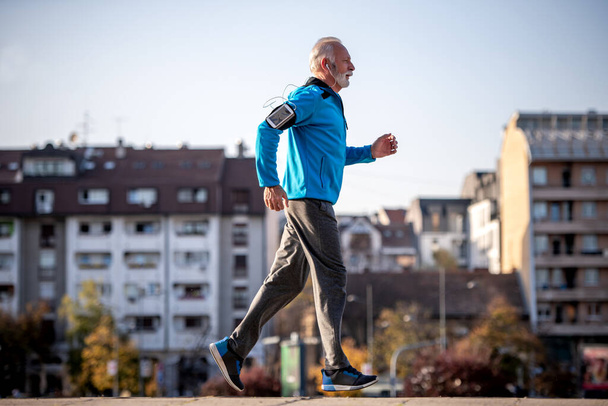 Senior man jogging in the city on sunny day. Fitness, sport, people and lifestyle concept. - Fotografie, Obrázek