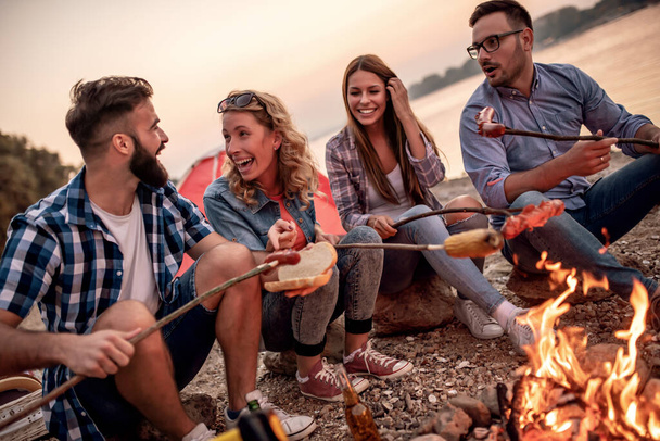 Barbecue.Young grupo de amigos grelhar salsichas ao ar livre, grelhar, pessoas e conceito de estilo de vida. - Foto, Imagem