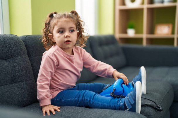 Suloinen valkoihoinen tyttö leikkii puhelimen lelu istuu sohvalla kotona - Valokuva, kuva