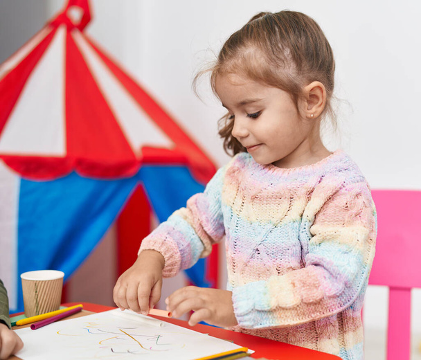 Чарівна іспаномовна дівчина студент малює на папері в дитячому садку
 - Фото, зображення