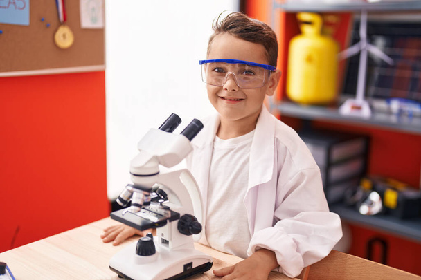 Adorabile studente ispanico bambino utilizzando il microscopio in piedi in classe - Foto, immagini