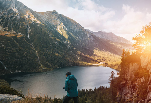 Fényképész fényképez gyönyörű hegyi természet a tóval. Utazás és aktív életmód koncepció.Fiatal férfi fotós fényképez egy digitális tükör nélküli fényképezőgép a hegyekben - Fotó, kép