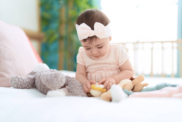 Adorable toddler playing with toys sitting on bed at bedroom - Foto, imagen
