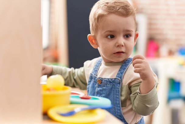 Adorable toddler playing with play kitchen standing at kindergarten - Foto, afbeelding