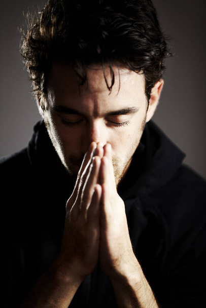 Głęboko się modli. Młody człowiek z dłońmi razem i zamkniętymi oczami w modlitwie - Zdjęcie, obraz