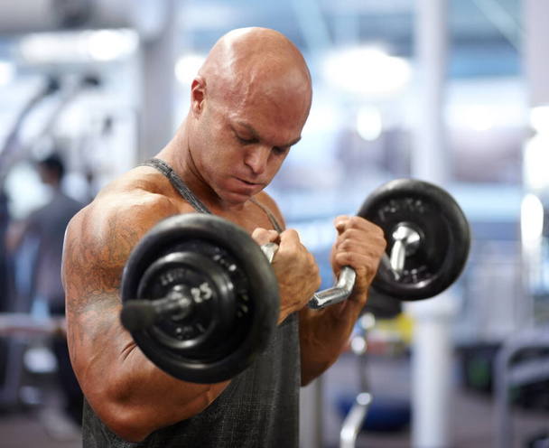 Trabajando esos bíceps. un culturista masculino levantando pesas en el gimnasio - Foto, imagen