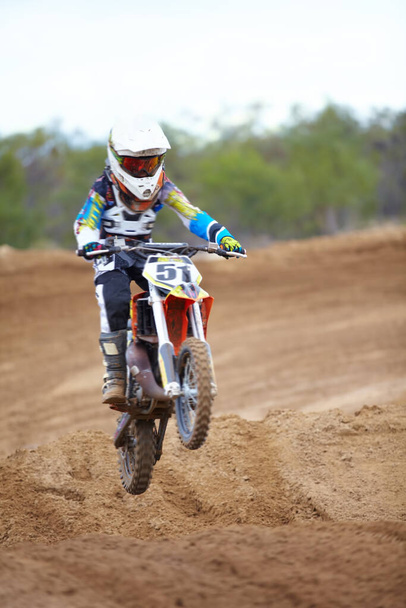 Hitting each ramp with purpose. A motocross rider taking a small jump - Foto, Imagem