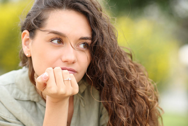 Serious woman with engagement ring looks away in a park - Foto, Imagen
