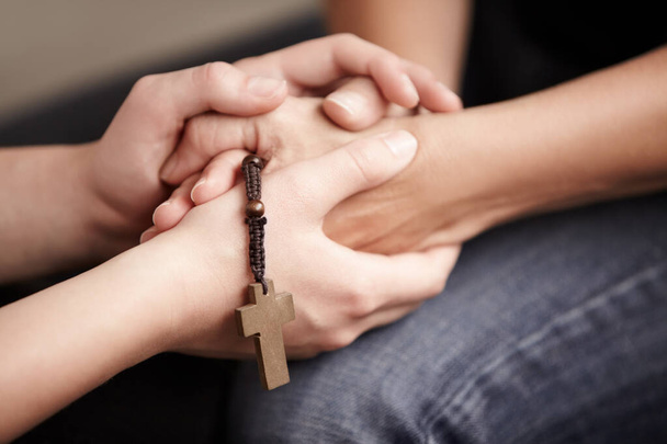 Su fe es fuerte. Manos sosteniendo un Rosario mientras se sostienen mutuamente - Foto, imagen
