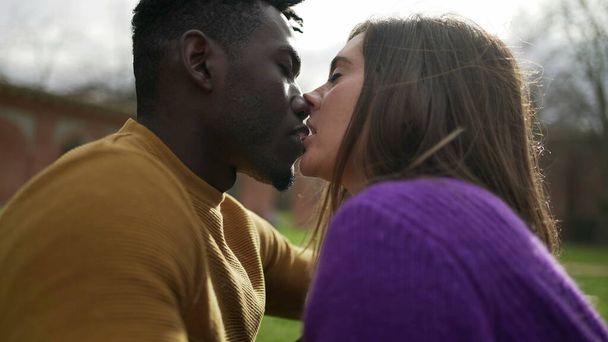 公園の外でキスしてる若い千年夫婦。親密な異人種間のキス - 写真・画像
