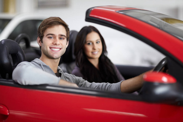 Feeling sporty. Attractive young couple trying out new cars at a dealership - Photo, Image