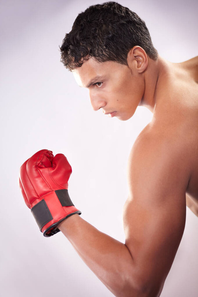 He fights like a finely tuned machine. A handsome young fighter pulling his bicep on a white background - Photo, Image