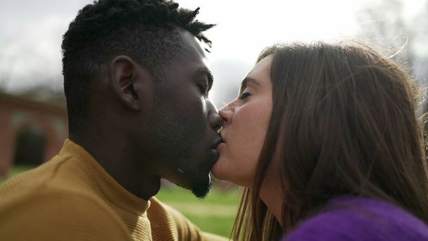 Young millennial couple kissing outside at park. intimate interracial kiss - Foto, Imagem