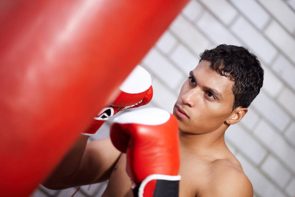 Float like a butterfly, sting like a bee. A young man practicing on a punching bag - Foto, Imagem