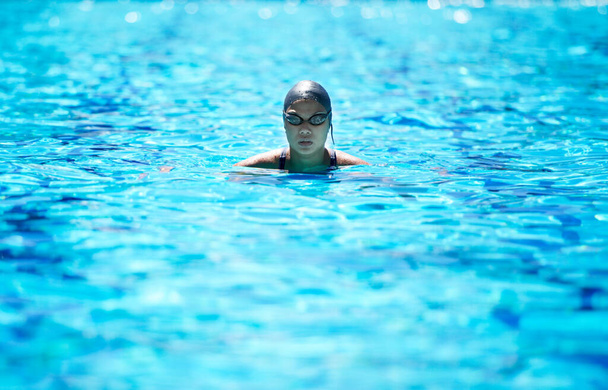 Past elke ronde bij elkaar. een vastberaden jonge vrouwelijke zwemmer in het water - Foto, afbeelding