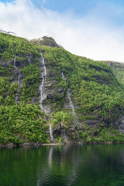 Красивый пейзаж со снежными горными вершинами и водопадами во фьорде Гейрангер, Норвегия - Фото, изображение