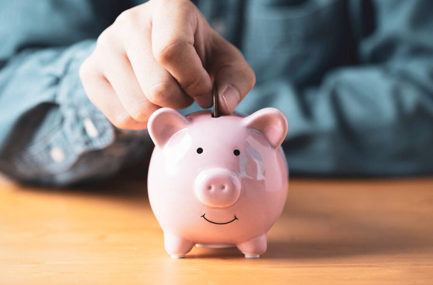 Бизнесмен вручную положить монету в розовый копилку для депозитного банкинга инвестиций, пенсии, чтобы получить прибыль и процентную концепцию. - Фото, изображение