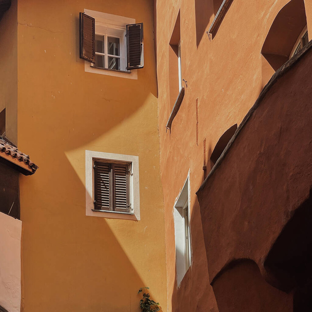 Историческая архитектура Италии. Традиционное старинное европейское здание с оранжевыми стенами, деревянными ставнями и окнами. Концепция эстетических летних каникул - Фото, изображение
