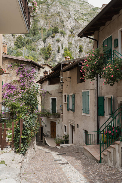 Kırsal İtalyan mimarisi. Geleneksel tarihi Avrupa kır binaları. Ahşap pencereleri, çiçekleri ve çiçek açan ağaçları var. Estetik yaz tatili seyahat kavramı - Fotoğraf, Görsel