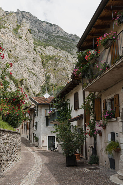 Ρουστίκ ιταλική αρχιτεκτονική. Ιταλικό χωριό στα βουνά με παραδοσιακά κτίρια, ξύλινα παράθυρα, λουλούδια και ανθισμένα δέντρα. Αισθητική έννοια καλοκαιρινών διακοπών - Φωτογραφία, εικόνα