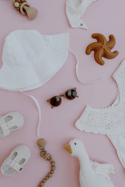 Σετ χαριτωμένα καλοκαιρινά ρούχα και αξεσουάρ για το κοριτσάκι σε ροζ φόντο. Επίπεδη lay, κορυφαία άποψη της κομψής συλλογής μόδας για το μικρό μωρό - Φωτογραφία, εικόνα