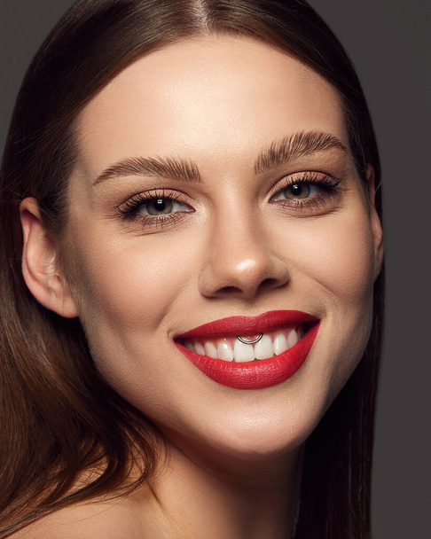 Close-up portrait of emotive beautiful young woman with green eyes smiling over dark grey background. Dental teeth care, whitening, Concept of beauty, fashion, makeup, magazine, emotions and ad. - Фото, изображение