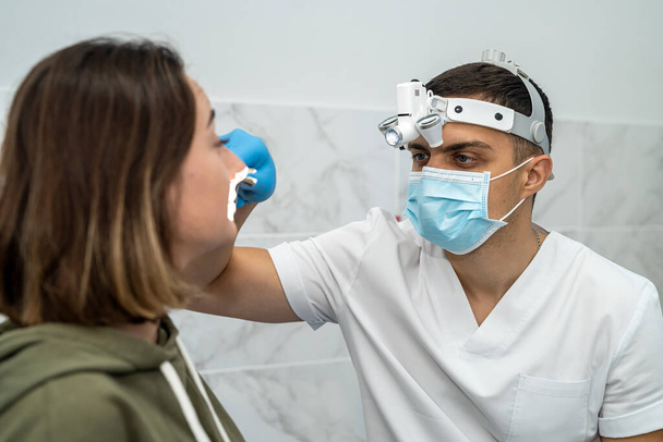 Лікар чоловічої статі вивчає ніс пацієнта з ринітом. Перевірка носа. Медичне обстеження носа. Концепція охорони здоров'я та медицини
. - Фото, зображення