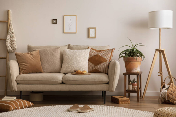 The stylish composition of living room interior with beige sofa with brown carpet, pillow, plaid, coffee table and personal accessories. beige wall with mock up poster. Home decor. Template. - 写真・画像