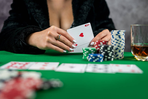 σέξι γυναίκα με χαρτιά πόκερ και μάρκες στα χέρια παίζοντας πόκερ στο τραπέζι. πόκερ παιχνίδι μια γυναίκα τυχερών παιχνιδιών σε ένα φόρεμα με ντεκολτέ - Φωτογραφία, εικόνα