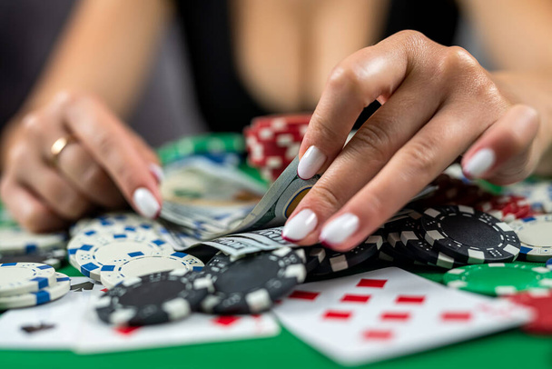 красивая женщина игрок считает фишки на деньги и повышает ставку во время игры в покер в казино. игорный бизнес. женщина в платье в казино - Фото, изображение