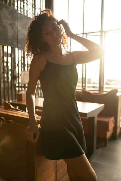 Portrait of a curly woman sitting in backlit. High quality photo - 写真・画像