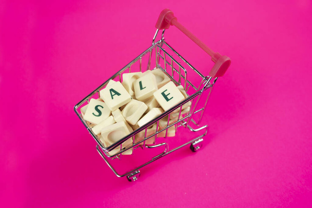 Sale text in shopping cart, shopping and commerce concept, shopping banner idea, supermarket trolley and letters, buying or selling idea, copy space - Photo, Image