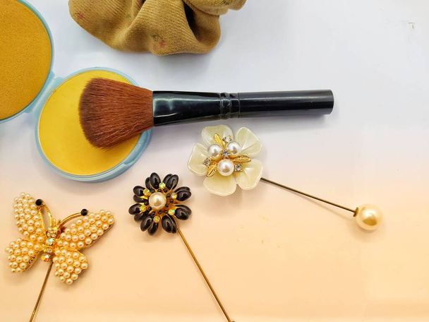 Kompaktowy proszek, szczotka do makijażu i dekoracja broszki izolowane na białym i żółtym tle - Zdjęcie, obraz