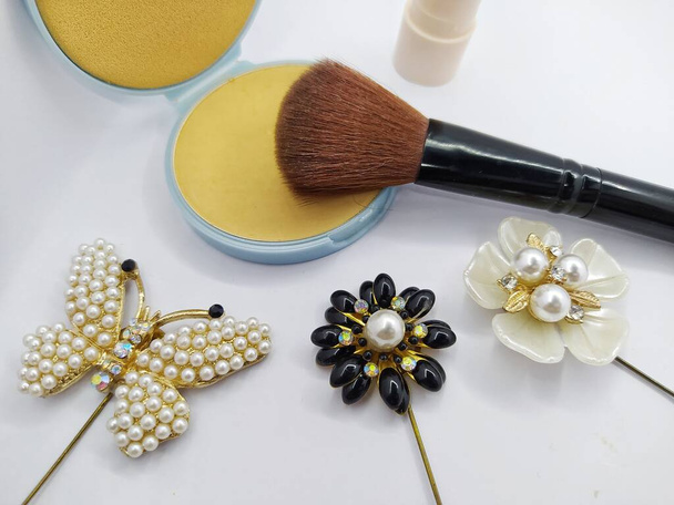 Compacte poeder, make-up borstel en broche decoratie geïsoleerd op witte achtergrond - Foto, afbeelding