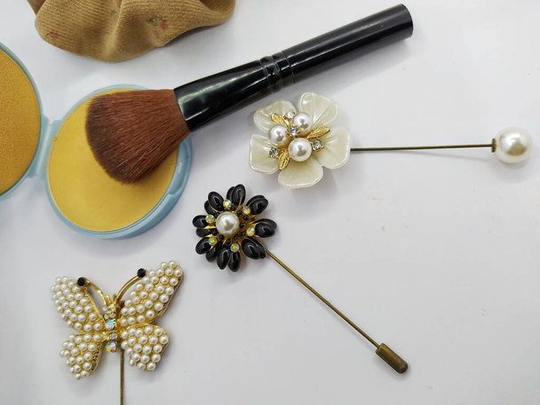 Polvo compacto, pincel de maquillaje y decoración de broches aislados sobre fondo blanco - Foto, imagen