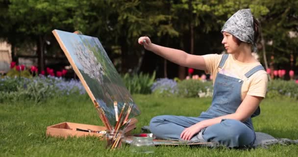 jonge vrouw schilderij bloemen in de tuin. - Video